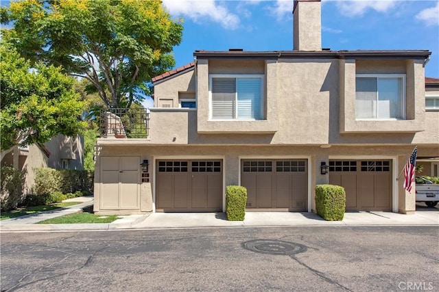 29 Stanford Ct Unit 93, Irvine, CA 92612 - view of front facade featuring stucco siding, a chimney, an attached garage, and a balcony