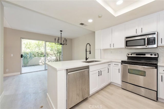 29 Stanford Ct Unit 93, Irvine, CA 92612 - kitchen featuring stainless steel appliances, decorative backsplash, a peninsula, white cabinetry, and recessed lighting