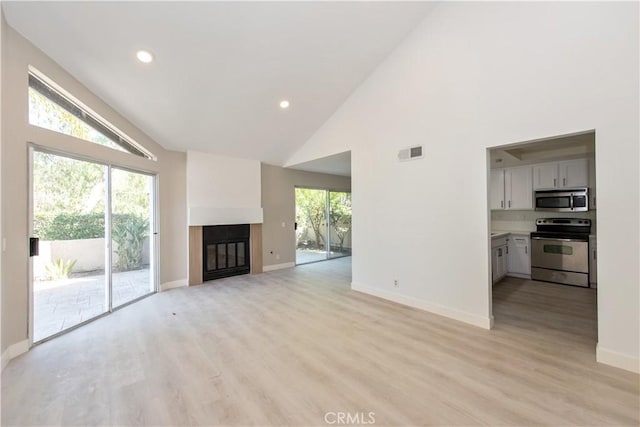 29 Stanford Ct Unit 93, Irvine, CA 92612 - unfurnished living room featuring high vaulted ceiling, a glass covered fireplace, light wood finished floors, and recessed lighting