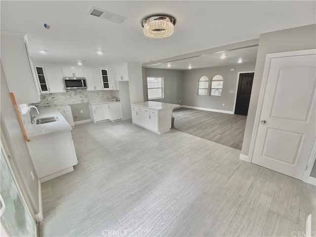 6545 Newlin, Whittier, CA 90601 - kitchen featuring stainless steel microwave, white cabinets, backsplash, glass insert cabinets, and open floor plan