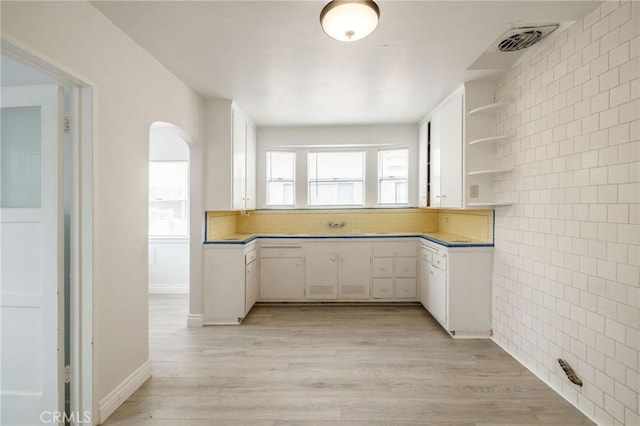 473 W 17th St, San Pedro, CA 90731 - kitchen featuring open shelves, tile walls, arched walkways, white cabinetry, and light wood-style floors