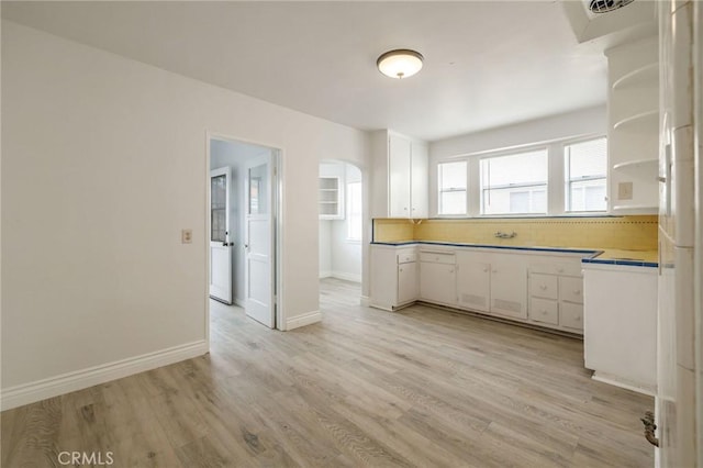 473 W 17th St, San Pedro, CA 90731 - kitchen featuring white cabinets, arched walkways, and light wood-style flooring