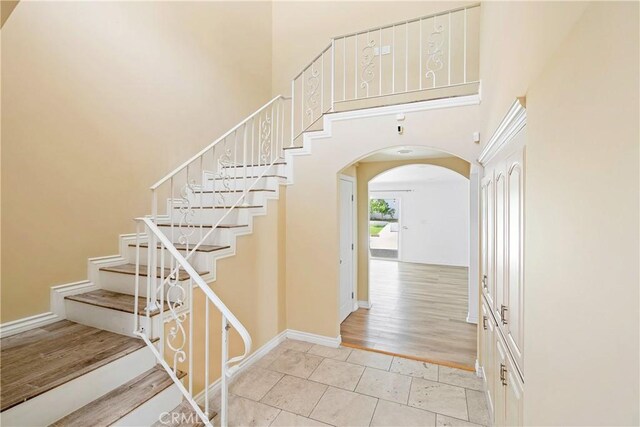 17211 Orozco St, Granada Hills, CA 91344 - entrance foyer with arched walkways, a towering ceiling, stairway, and light tile patterned floors