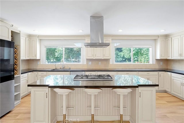 17211 Orozco St, Granada Hills, CA 91344 - kitchen featuring island exhaust hood, a kitchen island, stainless steel gas stovetop, decorative backsplash, and light wood-type flooring