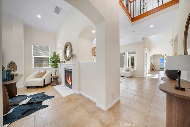 23735 Canyon Vista Ct, Diamond Bar, CA 91765 - entrance foyer with arched walkways, a high ceiling, a warm lit fireplace, light tile patterned floors, and recessed lighting