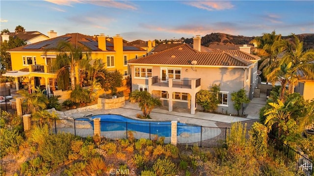 23735 Canyon Vista Ct, Diamond Bar, CA 91765 - back of house at dusk with a balcony, a fenced backyard, a chimney, stucco siding, and a tile roof