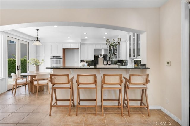 23735 Canyon Vista Ct, Diamond Bar, CA 91765 - kitchen with oven, white cabinetry, arched walkways, a kitchen breakfast bar, and dark countertops