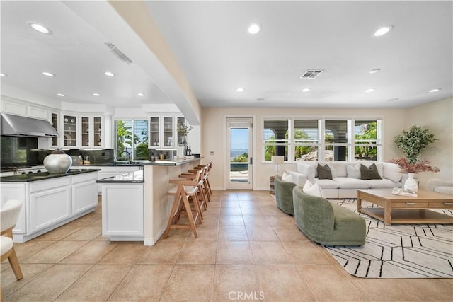 23735 Canyon Vista Ct, Diamond Bar, CA 91765 - kitchen featuring under cabinet range hood, plenty of natural light, a breakfast bar, white cabinetry, and recessed lighting