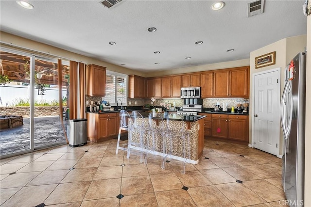 296 Lady Bell Way, Perris, CA 92571 - kitchen featuring appliances with stainless steel finishes, brown cabinetry, decorative backsplash, a center island, and recessed lighting