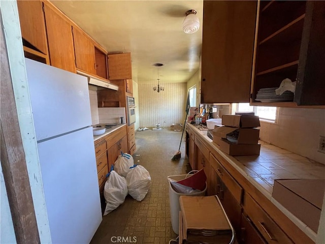 3917 Wood Ln, Bakersfield, CA 93309 - kitchen with freestanding refrigerator, tile countertops, brown cabinetry, oven, and cooktop