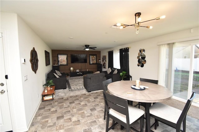 5280 Coyote St, Hemet, CA 92545 - dining room featuring a chandelier, a ceiling fan, an accent wall, wood walls, and stone finish flooring