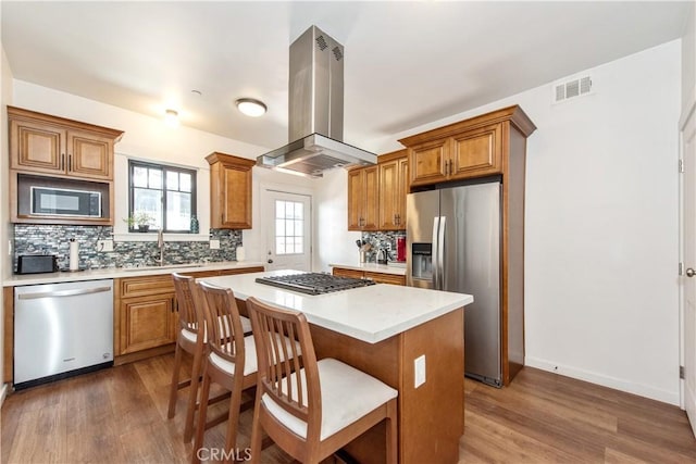 5336 Lemon Grove Ave, Los Angeles, CA 90038 - kitchen featuring stainless steel appliances, dark wood-type flooring, island exhaust hood, light countertops, and tasteful backsplash