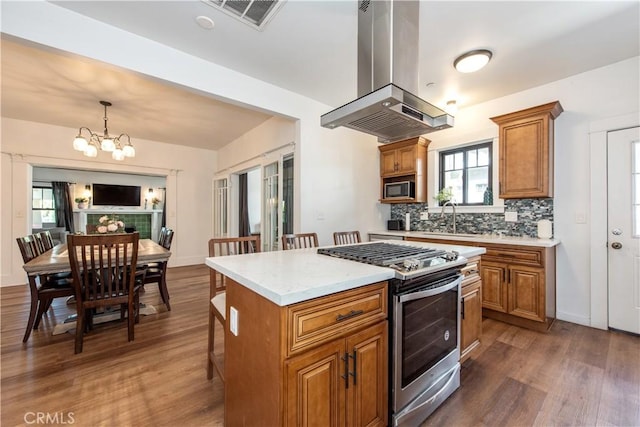 5336 Lemon Grove Ave, Los Angeles, CA 90038 - kitchen featuring appliances with stainless steel finishes, island exhaust hood, brown cabinets, dark wood-style floors, and a chandelier