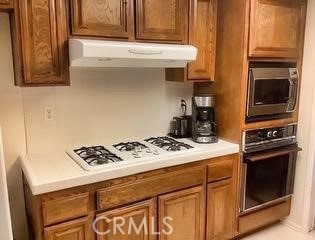 3526 Belle River Dr, Hacienda Heights, CA 91745 - kitchen featuring black oven, stainless steel microwave, brown cabinets, light countertops, and white gas cooktop