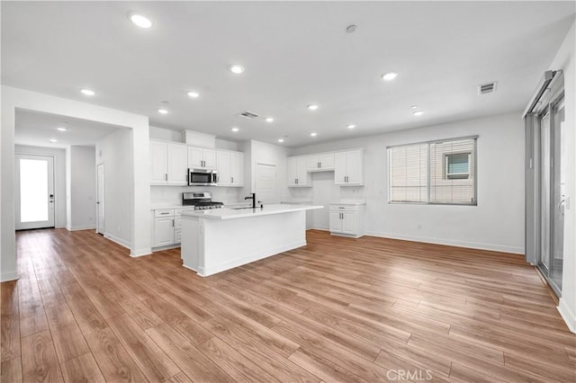 1660 Capri Way, Beaumont, CA 92223 - kitchen with white cabinets, light wood-style flooring, recessed lighting, appliances with stainless steel finishes, and a kitchen island with sink