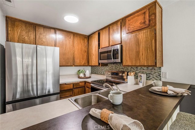 939 W Pine St Unit 44/D, Upland, CA 91786 - kitchen with stainless steel appliances, brown cabinets, tasteful backsplash, and a peninsula