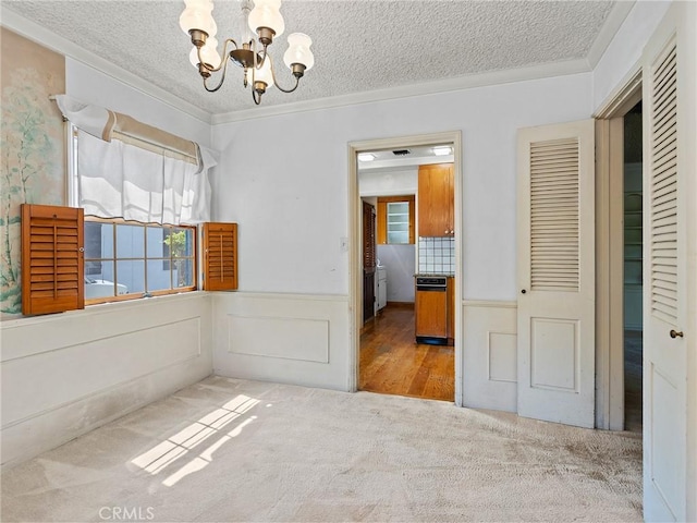 10348 Woodbridge St, Toluca Lake, CA 91602 - unfurnished dining area featuring a chandelier, carpet, a textured ceiling, wainscoting, and ornamental molding