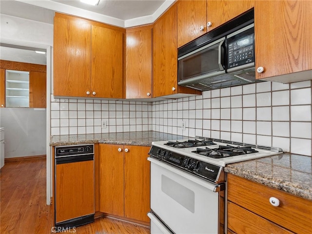 10348 Woodbridge St, Toluca Lake, CA 91602 - kitchen with white gas range, black microwave, brown cabinetry, and tasteful backsplash