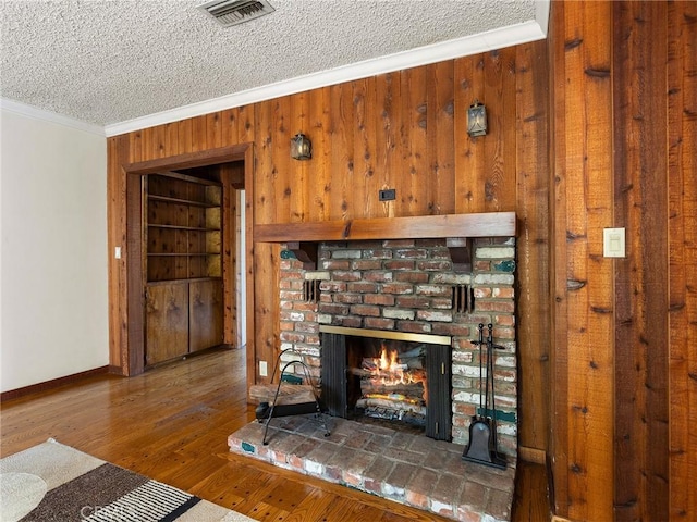 10348 Woodbridge St, Toluca Lake, CA 91602 - detailed view of ornamental molding, wooden walls, a brick fireplace, wood finished floors, and a textured ceiling