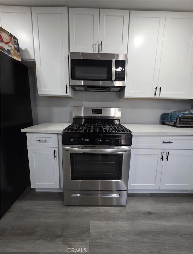 460 E 2nd St, San Jacinto, CA 92583 - kitchen with appliances with stainless steel finishes, wood finished floors, light countertops, and white cabinets