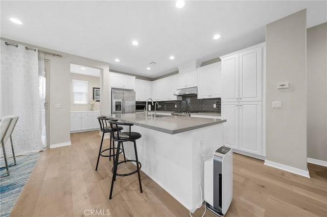 20950 Cornerstone Dr, Walnut, CA 91789 - kitchen featuring light wood-style floors, a kitchen bar, tasteful backsplash, white cabinetry, and recessed lighting