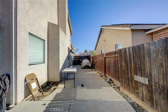 1166 Labrador Ct, Newman, CA 95360 - view of side of home with a fenced backyard, a patio, and stucco siding