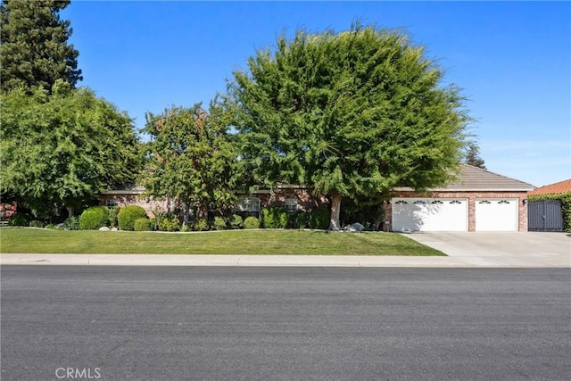 8905 Saint Cloud Ln, Bakersfield, CA 93311 - obstructed view of property with a front lawn, driveway, a garage, and brick siding