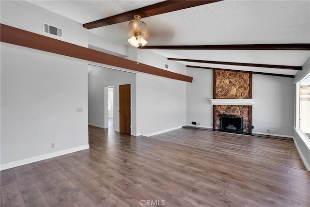 26453 Buccaneer Ln, Helendale, CA 92342 - unfurnished living room featuring a textured ceiling, beam ceiling, a stone fireplace, ceiling fan, and dark wood finished floors
