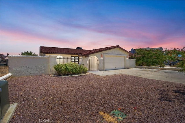 26453 Buccaneer Ln, Helendale, CA 92342 - mediterranean / spanish-style house with concrete driveway, a fenced front yard, a garage, stucco siding, and a tile roof