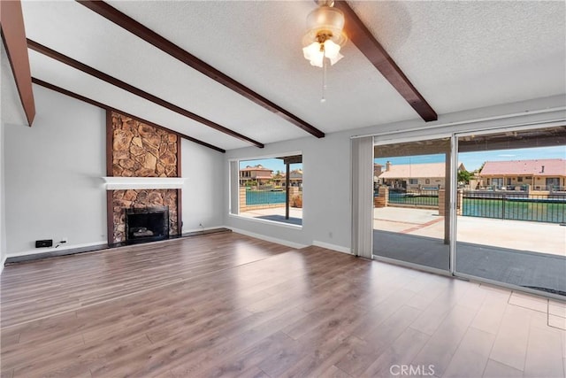26453 Buccaneer Ln, Helendale, CA 92342 - unfurnished living room with wood finished floors, a fireplace, a textured ceiling, and a ceiling fan