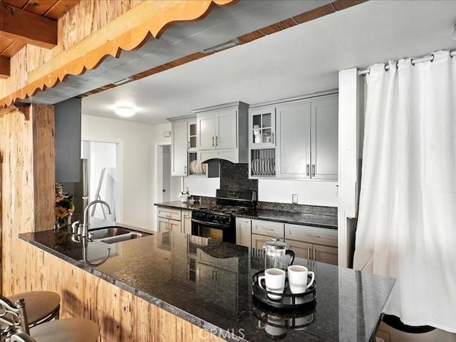 20319 Vanowen St, Winnetka, CA 91306 - kitchen with a breakfast bar, black gas stove, dark stone counters, and glass insert cabinets