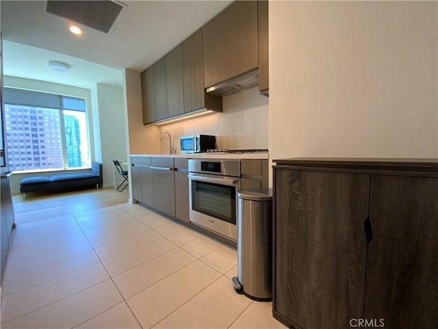 889 Francisco St Unit 1105, Los Angeles, CA 90017 - kitchen with stainless steel appliances, under cabinet range hood, gray cabinetry, light tile patterned floors, and light countertops
