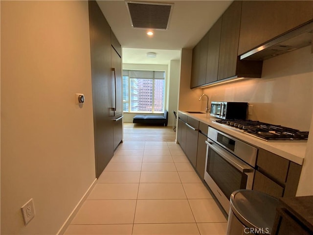 889 Francisco St Unit 1105, Los Angeles, CA 90017 - kitchen featuring appliances with stainless steel finishes, light tile patterned floors, ventilation hood, and light countertops