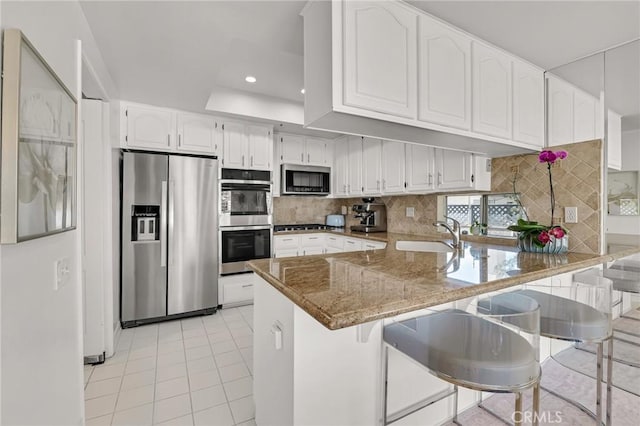 5224 Zelzah Ave Unit 208, Encino, CA 91316 - kitchen featuring a peninsula, stainless steel appliances, light tile patterned flooring, white cabinetry, and tasteful backsplash