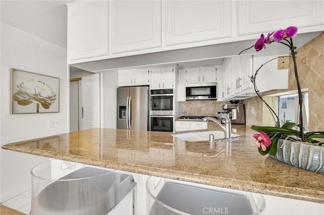 5224 Zelzah Ave Unit 208, Encino, CA 91316 - kitchen with a peninsula, stainless steel appliances, white cabinetry, and light stone countertops