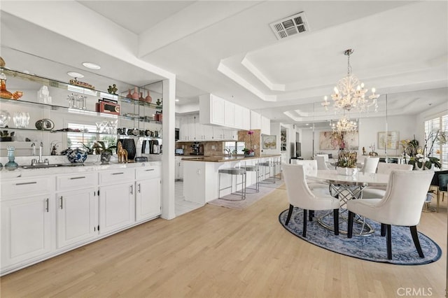 5224 Zelzah Ave Unit 208, Encino, CA 91316 - dining area with light wood finished floors, a chandelier, and a raised ceiling