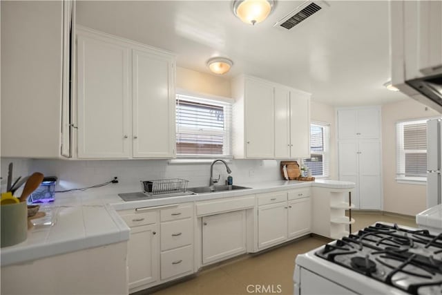 33 Miner St, Bakersfield, CA 93305 - kitchen featuring tile counters, white cabinetry, gas range gas stove, tasteful backsplash, and fridge