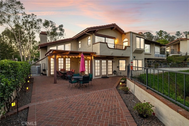 1610 Via Estrella, Pomona, CA 91768 - back of house at dusk featuring french doors, a chimney, stucco siding, a patio, and a tile roof