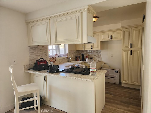 17077 Los Modelos St, Fountain Valley, CA 92708 - kitchen with cream cabinetry, decorative backsplash, wood finished floors, a peninsula, and light stone countertops