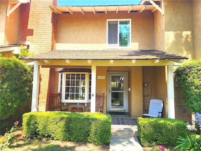 17077 Los Modelos St, Fountain Valley, CA 92708 - property entrance with a porch, stucco siding, roof with shingles, and brick siding