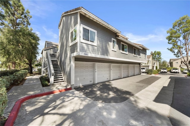 45 Bramble Ln Unit 109, Aliso Viejo, CA 92656 - view of property exterior featuring stairs, concrete driveway, an attached garage, and a residential view