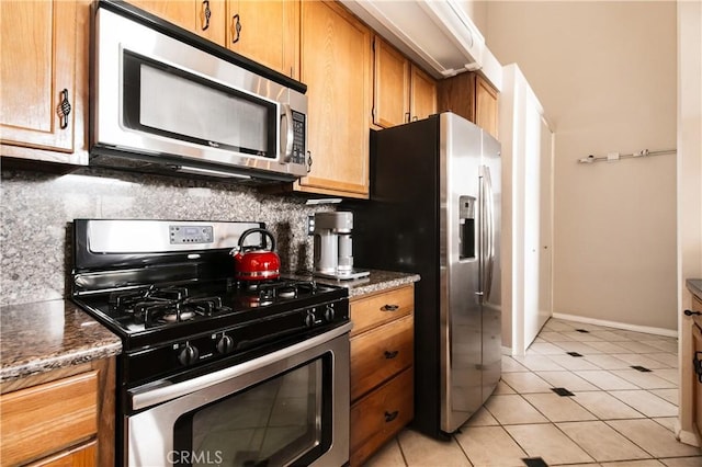 5440 Lindley Ave Unit 310, Encino, CA 91316 - kitchen featuring stainless steel appliances, tasteful backsplash, light tile patterned floors, brown cabinets, and dark stone countertops