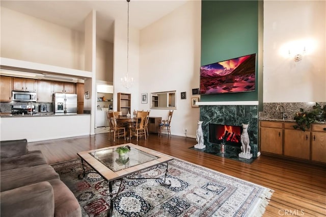 5440 Lindley Ave Unit 310, Encino, CA 91316 - living area with a towering ceiling, wood finished floors, a chandelier, and a premium fireplace