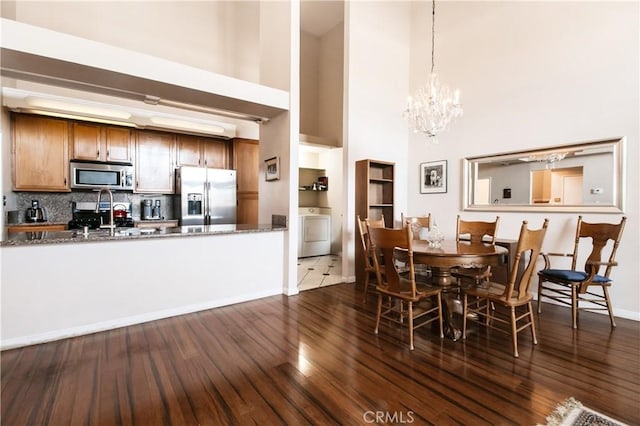 5440 Lindley Ave Unit 310, Encino, CA 91316 - dining room featuring a towering ceiling, dark wood-style floors, a chandelier, and washer / clothes dryer