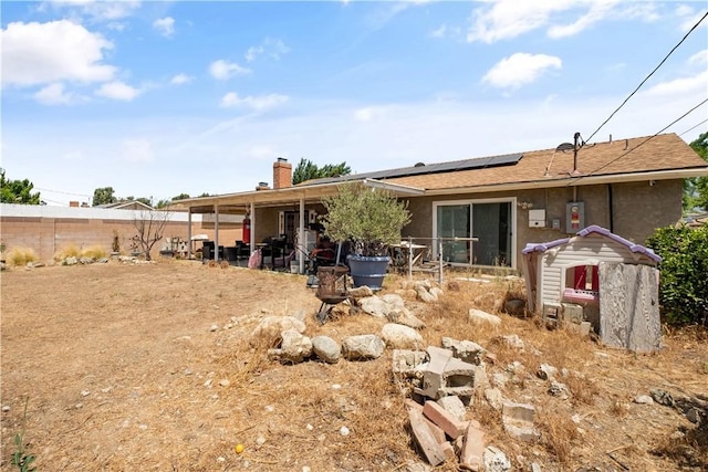 1062 Golden Rain St, Upland, CA 91786 - back of property with solar panels, stucco siding, a fenced backyard, a chimney, and a shingled roof