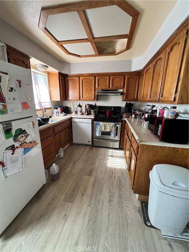 7512 Xavier Ave, California City, CA 93505 - kitchen with brown cabinetry, white appliances, light countertops, light wood-style floors, and coffered ceiling