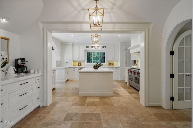 1370 Hillcrest Ave, Pasadena, CA 91106 - kitchen with arched walkways, a chandelier, white cabinetry, and stone tile flooring