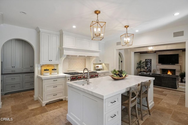 1370 Hillcrest Ave, Pasadena, CA 91106 - kitchen featuring stone tile floors, a kitchen island with sink, backsplash, a chandelier, and a breakfast bar