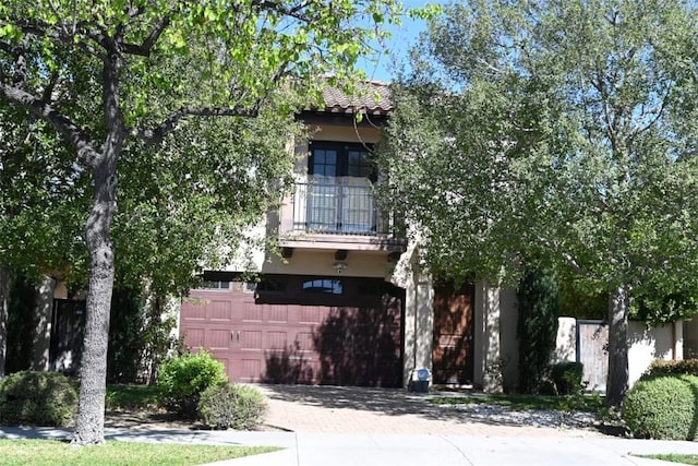 31 Alta St Unit A, Arcadia, CA 91006 - view of property hidden behind natural elements featuring a balcony, decorative driveway, stucco siding, and a garage