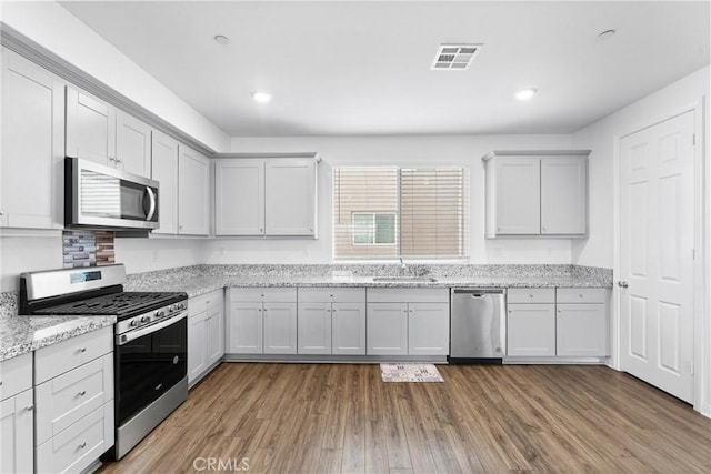 14053 Spurlock Ln Unit 3, Gardena, CA 90247 - kitchen with appliances with stainless steel finishes, wood finished floors, light stone counters, and recessed lighting